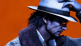 A man wears a white hat and suit in front of an orange background.