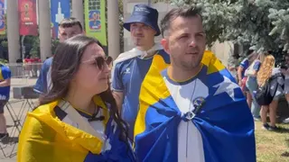 A woman on the left and a man on the right, both with a blue and yellow flag on them.