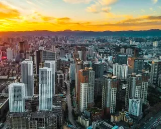 Aerial view of Kunming at sunset, with high-rise buildings and mountains in the distance