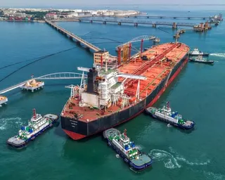 Tugboats move a crude oil tanker to its berth at the oil terminal at the port in Qingdao, China