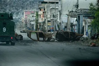 A police vehicle drives around cars burned by armed gangs in Haiti’s capital Port-au-Prince in January. Kidnappings are increasingly occurring in areas of Port-au-Prince once considered safe. Photo: TNS