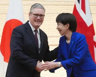 British Prime Minister Keir Starmer and Japanese Prime Minister Sanae Takaichi shake hands and smile before flags