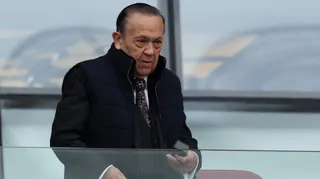David Sullivan wears a black gilet, black suit, white shirt and patterned tie and has combed back hair. He is looking on during a West Ham match at London Stadium