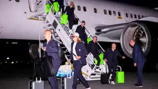 A group of men getting out of a plane with bright green suitcases.