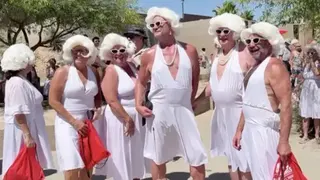 A group of people dressed in white dresses and wigs posing as Marilyn Monroe lookalikes.