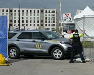 man holds fence and looks to side next to SUV marked 'missouri state highway patrol'