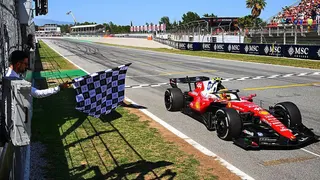 Lewis Hamilton crossing the line with Novak Djokovic waving the flag