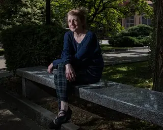 Cattaneo seated on a stone bench under trees in an urban park
