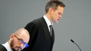 AFP via Getty Images A man in a gown and tie speaks in front of a microphone