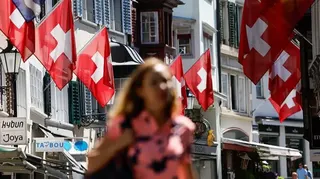 Pedestrians pass Swiss national flags in Zurich, Switzerland