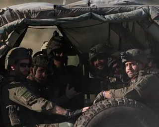 Half-a-dozen soldiers look out at the camera while sat in the back of a military vehicle