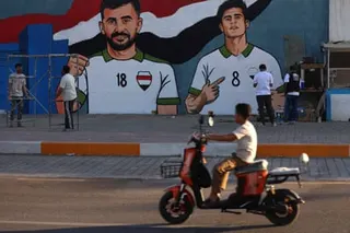 Aymen Hussein (no 18) is shown as part of an art project depicting Iraq’s national football team on the wall of a police station in Sadr City, Baghdad shows alongside Ibrahim Bayesh.