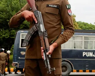 a Pakistani police officer holds a firearm