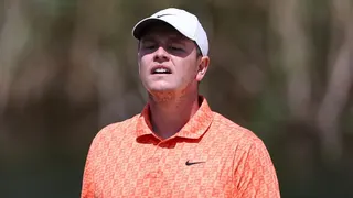 Close up of Bob MacIntyre with his cap casting a shadow over his face as he watches a putt go towards the hole