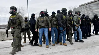 Federal law enforcement agents standing guard facing anti-ICE protesters outside the Bishop Whipple Federal Building in Minneapolis