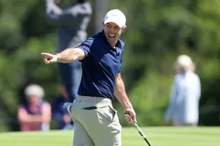 Rory McIlroy points and smiles on the course