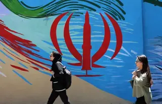 EPA Two Iranian women walk past a wall painting of Iran's national flag on a street in Tehran.