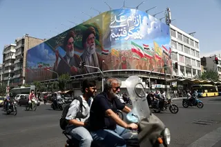 People ride past a billboard depicting the late leader of the Islamic Revolution, Ayatollah Ruhollah Khomeini, and the late Iran's Supreme Leader Ayatollah Ali Khamenei,