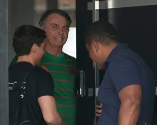 Jair Bolsonaro stands in a doorway with two other men.