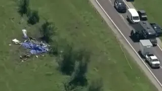 A view of the crash site on the left with vehicles parked along the road to the right