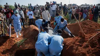 Family members and a group of midwives cry upon the arrival at the cemetery of the casket containing the body of their relative, who died from Ebola, as it is lowered into a grave in Bunia, Ituri Province, Democratic Republic of the Congo