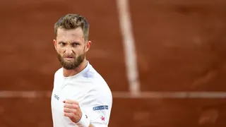 Corentin Moutet reacting during a tennis match against Novak Djokovic at Roland Garros Stadium.