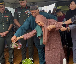 Siti Khadijah’s parents, Sungip Jais and Zaliha Said, pour water on the grave. Zaliha, overcome with grief, had to be consoled by family members. NSTP/ALIAS ABD RANI