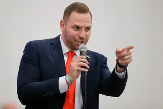 a man points while speaking into a microphone