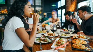 Person eating at the table with a bunch of food in front of them