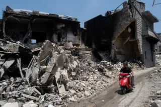 Men ride a motorcycle past buildings damaged by Israeli strikes in Nabatieh, Lebanon, on Wednesday. Photo: Reuters