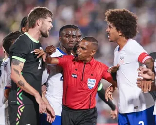 Referee Kwinsi Williams gestures between players from two teams during a heated moment on a soccer field