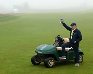 Foggy conditions at Shinnecock Hills as a rules official blows the horn to signal a suspension of play due to limited visibility on Thursday.