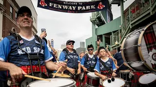 A pipe band outside Fenway Park wearing tartan tops bearing the words "Rex Sox"