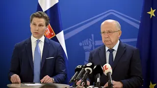 two officials in suits speaking at press conference