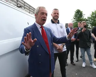 Farage standing in front of a white van next to Kenyon, who is dressed in an England shirt.