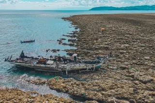 A fishing boat is stranded after the seabed is thrust upwards by the June 8 earthquake in the Philippines. Photo: AFP