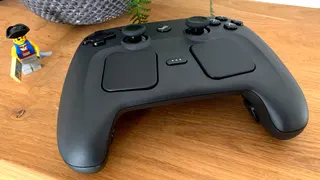 A photo of Valve's new Steam Controller sitting on a wooden shelf next to a fern and a fearsome Lego pirate.