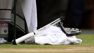 Novak Djokovic holding a smashed tennis racket during a match at Wimbledon.