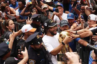 NBA总决赛最有价值球员布伦森（戴帽白衣）抱着NBA冠军奖杯，和球迷一起庆祝。（路透社）