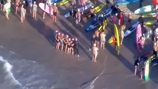 An aerial grab from video shows swimmers standing on the beach next to surfers with their boards before they paddle out, in Bondi on Friday.