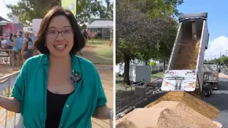 A woman in a green shirt stands in front of registration tents, with a truck pouring sand on the street visible to her right.