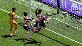 United States' Alex Freeman heads the ball past Australia goalkeeper Patrick Beach in a soccer match.