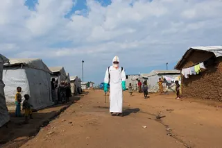 Displaced people watch a health worker in full personal protective equipment preparing to disinfect the area during the burial of Ebola victims at the Kigonze camp on Thursday. Photo: Reuters