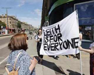 People on the street hold up a sign that says: ‘Leith is for everyone’
