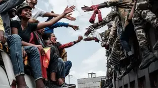 AFP via Getty Images TPLF supports on a bus reach out to touch hands with Tigray soldiers in Mekelle, Tigray - 2021