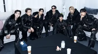 Big Hit Music The seven BTS members, dressed in black from top to toe, sitting around a couch before their show in Goyang, South Korea