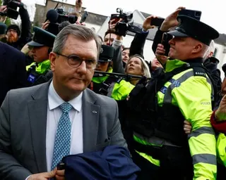 Jeffrey Donaldson walks past police officers and media with cameras outside court