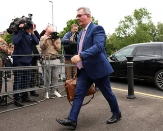 Jeffrey Donaldson walks past media cameras and barriers outside a courthouse