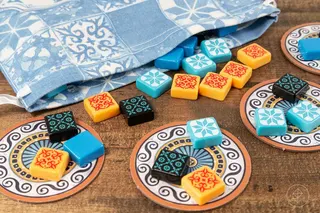 A bag with multicolored tiles pouring out of it from the board game Azul