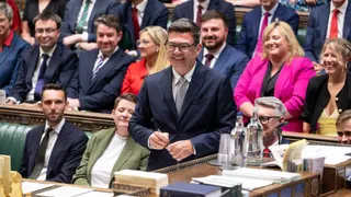 A handout photograph released by the UK Parliament shows new Labour Party MP for Makerfield, Andy Burnham (C) smiles after signing the book having been sworn in after his win in the recent by-election